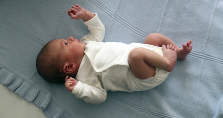 Newborn baby infant during first week of life, baby laid in bed seen from above