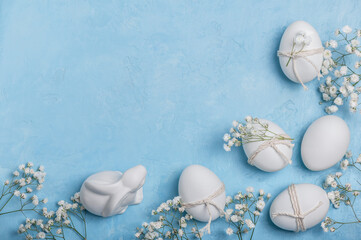Fototapeta na wymiar White Easter eggs decorated with twine and sprigs of gypsophila on a blue background. Easter greeting concept.Easter background.