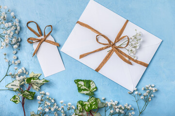White envelope and gift label on a blue background with sprigs of gypsophila. Happy Easter greeting card, Happy Birthday, Mother's Day, Happy Wedding Day.