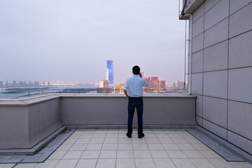 Businessman standing on the rooftop and using phone