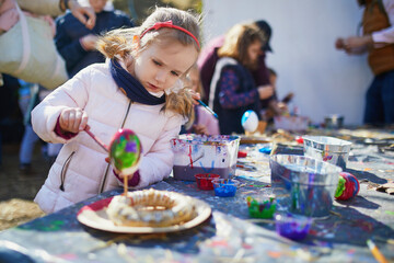 Adorable preschooler girl making diy Easter craft outdoors