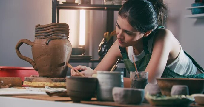 A female ceramicist is creating a new pottery in the workshop. Asian woman is enjoying pottery work.