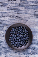 from above, on a textured background, a black plate with fresh blueberries. Empty space. - 724835378