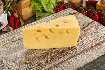 Swiss Maasdam cheese triangle over board