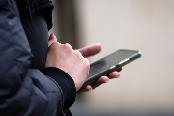 Female hands with smartphone close up. Woman using mobile phone on a city street