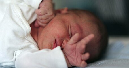 Newborn baby sleeping, infant stretching face and waking up