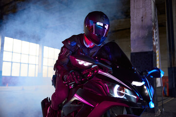 Portrait of motor biker driving sport motorcycle in neon light
