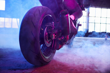 Closeup sport motorcycle wheel view from back in neon light and smoke