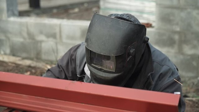 Welder in protective helmet uses welding. Welder Welds a metal pipe. Iron welding. Welding Sparks