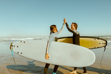 Two surfers greet each other by shaking hands before surfing on waves in ocean
