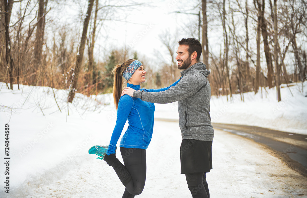 Wall mural active runner couple jogging together in snowy path in nature.