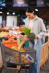 Young woman chooses broccoli, buying vegetables in supermarket.
