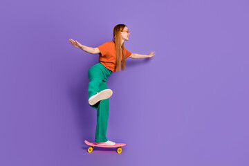 Fototapeta na wymiar Photo of lovely pretty good mood girl dressed stylish clothes riding long board empty space isolated on purple color background