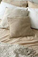 pillows in beige tones lie on the bed in the bedroom, close-up view, minimalism, concept quiet luxury