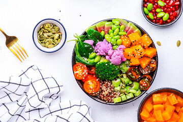 Vegan buddha bowl with pumpkin, quinoa, tomatoes, spinach, celery, edamame, tofu, cauliflower,...