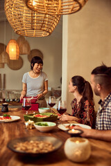 Happy friends having a birthday dinner, opening a gift.