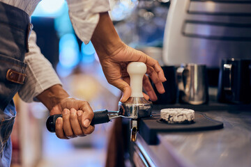 Side view of a female barista, making a coffee, at work.