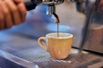 Close-up of a small cup, pouring a coffee into it, an espresso.