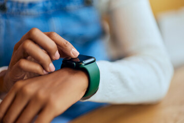 Close-up of a black female using a smartwatch, wearing around the wrist. - obrazy, fototapety, plakaty