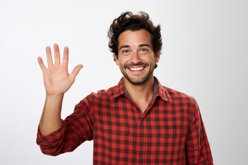 Fototapeta premium A man wearing a red and black checkered shirt holds his hand up in the air.