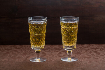 Sparkling champagne in two glasses on a brown tablecloth.