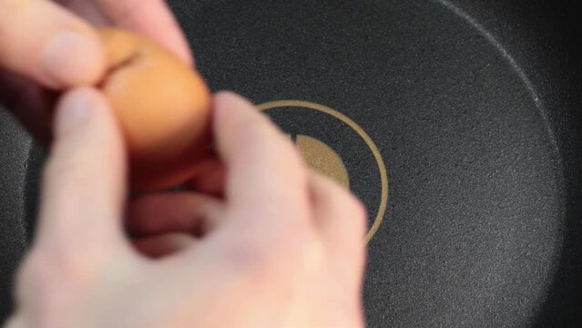 Close up man hands throwing broken egg on pan with a dispenser. Slow motion footage.