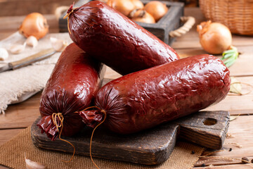 Smoked sausage on a wooden table with addition of fresh aromatic herbs and spices, natural product...