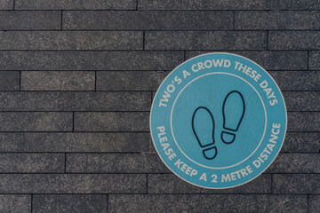 Two is a crowd these days please keep a 2 metres sign on a pavement in London, UK.