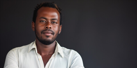 Obraz premium Casual young African man with a serene expression against a dark gray background