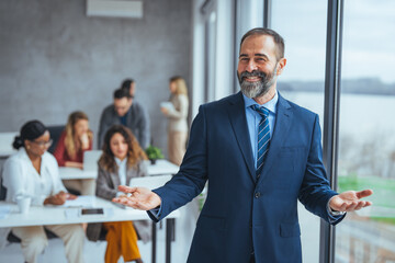 Confident businessman posing in the office, he is smiling at camera. Portrait of happy mature businessman looking at camera. Multiethnic satisfied man with beard feeling confident at office.