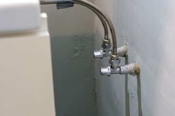 Hoses from the Wash Basin Intertwined with Taps Through Adapters in the Bathroom.