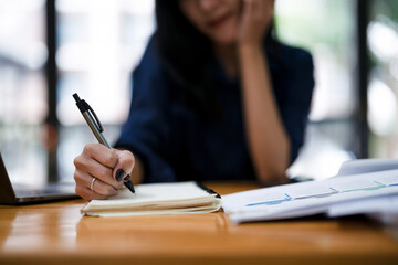 Close up of businesswoman's hands writing something with pen on her notebook. cropped image