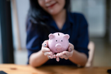 Obraz na płótnie Canvas A female's hands holding a piggy bank. Saving money, financial