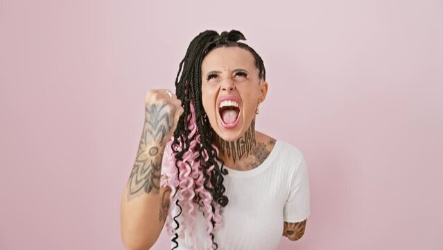 Frustrated hispanic amputee woman, crazy with rage, standing furious over pink isolated background, handless and mad, punching air with the spirit of fight