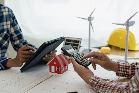 Construction crews begin new project plans to discuss a renewable energy construction project that includes wind turbines and solar cells. and the house on the table in the close-up