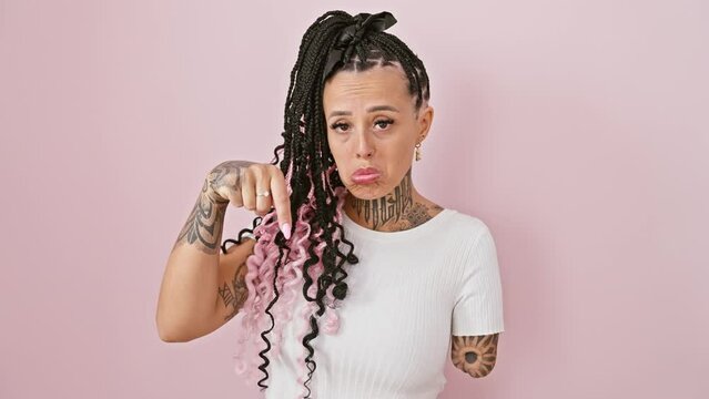 Upset hispanic woman amputee, sad and depressed, indicating down wih finger over isolated pink background