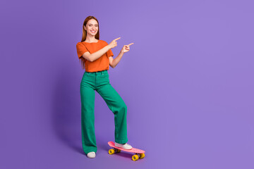 Photo of adorable cheerful girl wear stylish clothes two arm demonstrate empty space news offer isolated on purple color background