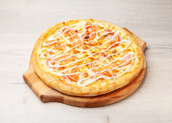 Pizza with chicken, tomato, cheese and white sauce on a wooden board