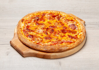 Meat pizza with ham, sausage and cheese on a wooden board