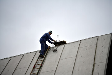 A  chimneyer climbs a ladder to the roof to repair a chimney - 724893393