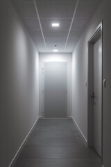 Hallway with light above door that is open leading to darker area.