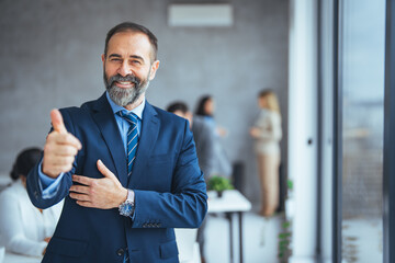 Cheerful businessman thumbs up posing and smiling at camera.  Portrait of happy business man...