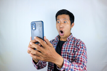 funny facial expression of asian man shocked and shocked holding and looking at phone screen