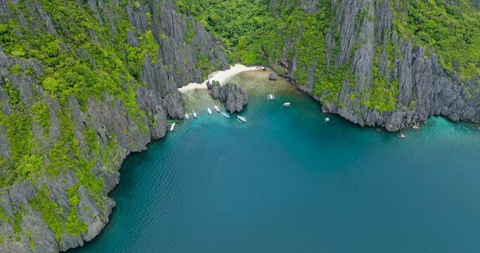 Splendid limestone rock formations in Secret Lagoon and Jiji's Beach with boats. El Nido, Palawan. Philippines.