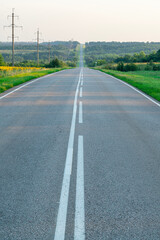 Obraz premium an asphalt road stretching to the horizon among the fields