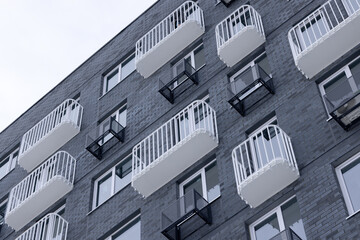 White narrow balconies and boxes for installing air conditioning on the wall of a gray brick house