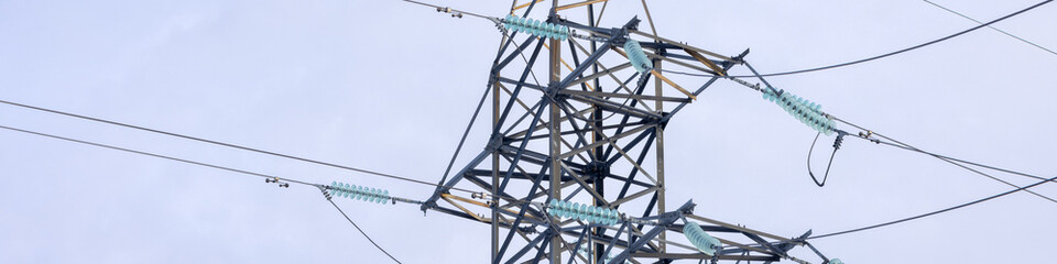 banner is 4x1 Part of an electric line support with insulators and wires on a blue sky background