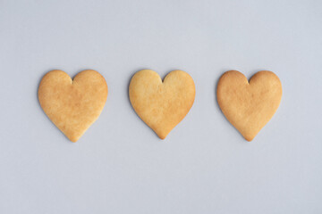 Homemade heart-shaped biscuits on grey background, top view