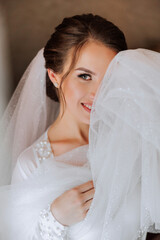 Beautiful bride in a dressing gown in the morning before the wedding ceremony. Incredible hairstyle of the bride. Natural and modern makeup. Portrait of a young bride in a dressing gown.