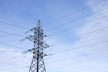A high-voltage mast with wires against a clear blue sky. Bottom view.